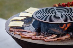 burgers and bacon cooking on a plancha