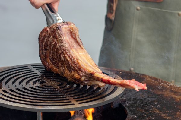 tomahawk steak cooking on an outdoor grill