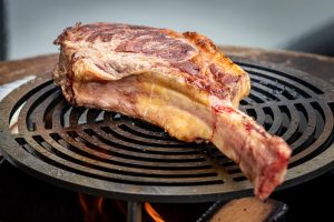 a wagyu tomahawk being cooked on a Quoco Plancha rather than a cheap BBQ grill